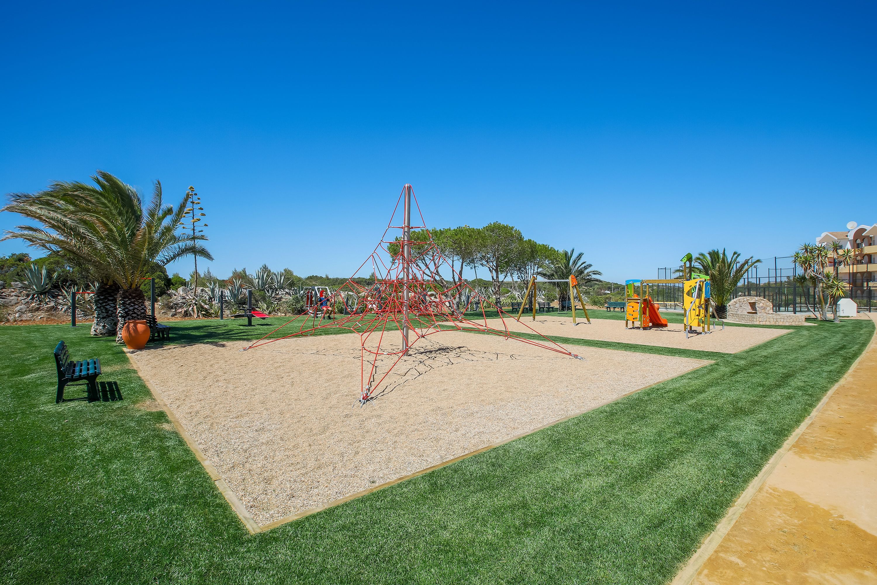 A playground with a sandpit, swings, and a climbing structure.