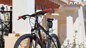 A mountain bike parked against a building with a white facade and a red roof.