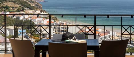 Un balcon avec une table et des chaises donnant sur une plage et la ville.
