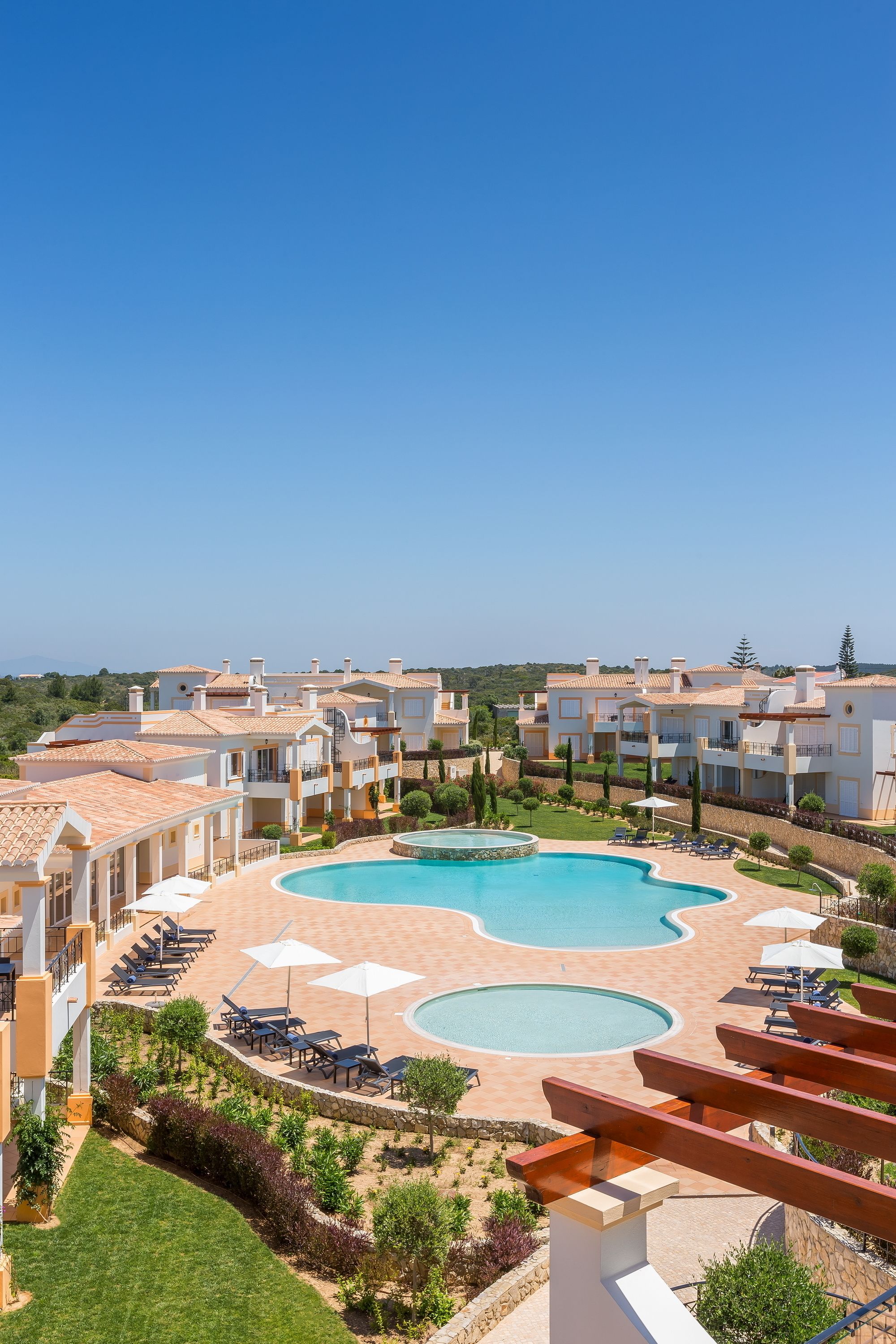 A resort with multiple buildings, a large central pool, and outdoor seating areas.