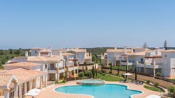 A resort with multiple buildings, a large central pool, and outdoor seating areas.