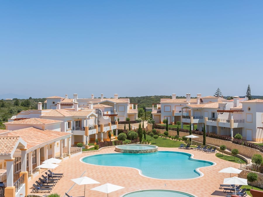 Ein Resort mit mehreren Gebäuden, einem großen zentralen Pool und Außen-Sitzbereichen.