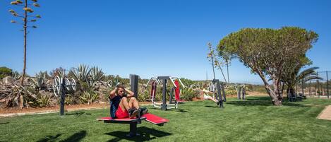 An outdoor exercise area with exercise equipment and a grassy field.