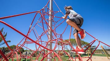 A child climbing a red rope structure at a playground.