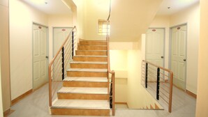 A multi-level interior with a central staircase, multiple doors, and a light-colored floor. - Anri Pension House (Cebu City)
