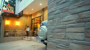 A building entrance with a sign for ANRI Pension House, a security guard, and a parked vehicle. - Anri Pension House (Cebu City)