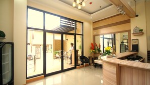 A spacious room with a large sliding glass door leading to an outdoor area, a wooden reception desk, and a chair. - Anri Pension House (Cebu City)