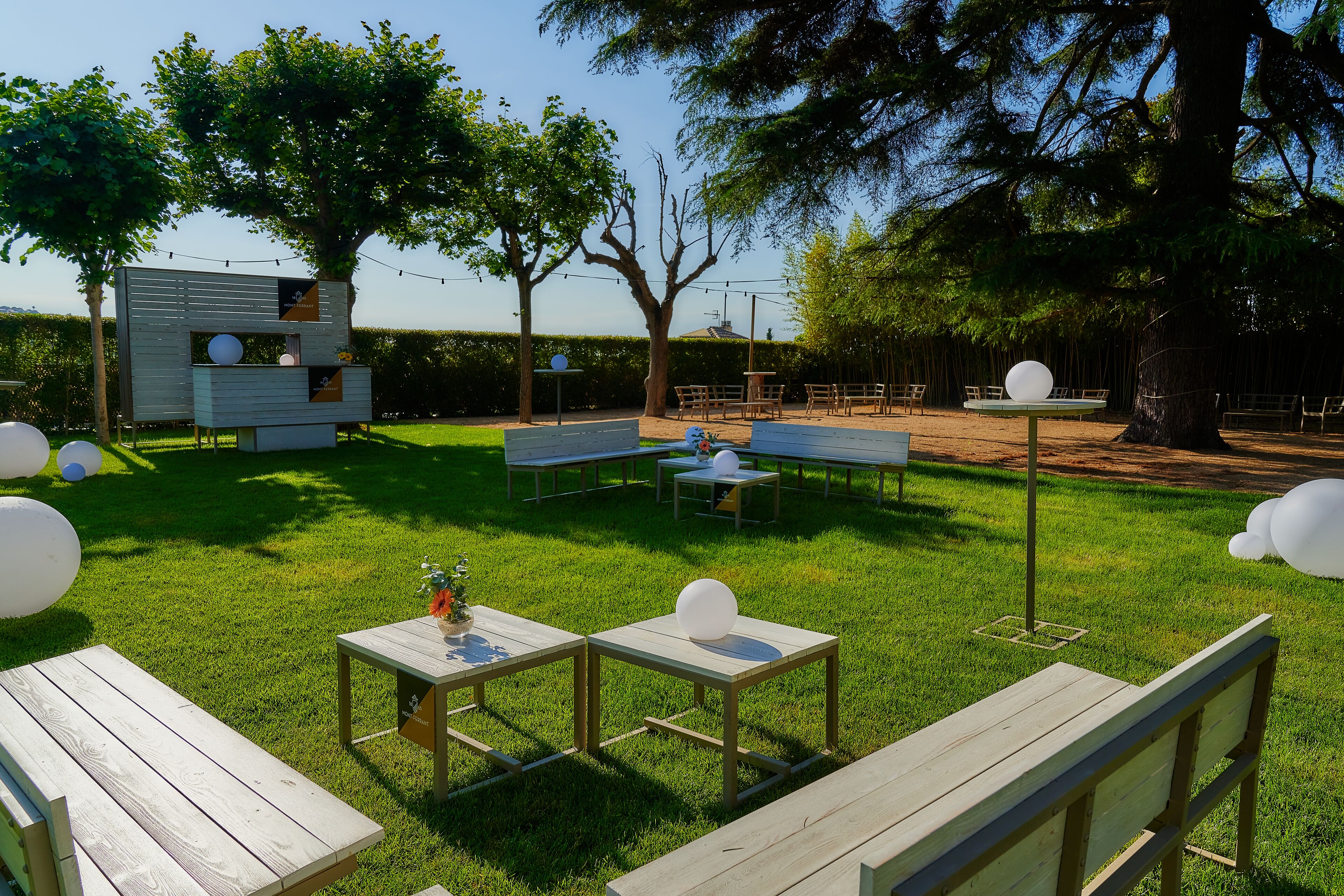 An outdoor area with picnic tables, benches, and a small structure with a window.
