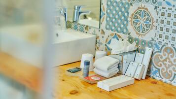 A bathroom with a sink, mirror, and patterned tiles. There are toiletries and a towel on the counter.
