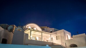 Un edificio moderno blanco con un balcón que da a un patio, bajo un cielo nocturno.