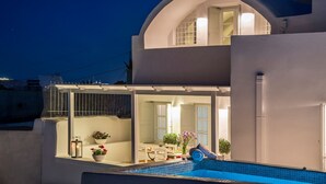 Un edificio de dos pisos con piscina, un patio cubierto y vistas al mar.