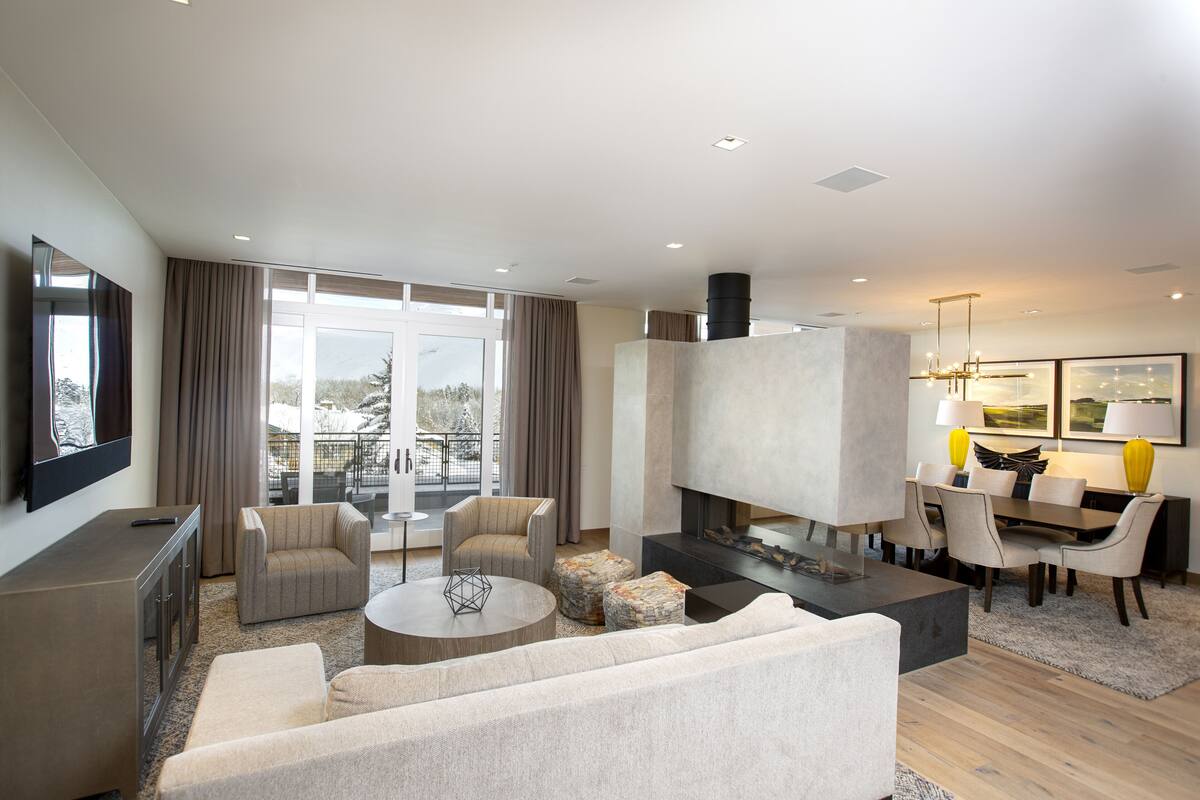 Un salon moderne doté d’une cheminée, de sièges confortables et d’un coin repas.