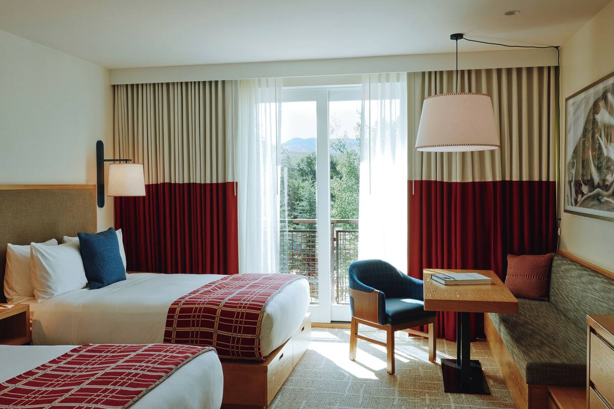 Une chambre d’hôtel avec un lit, un canapé, une table avec une lampe et une vue sur l’extérieur grâce à une grande fenêtre.