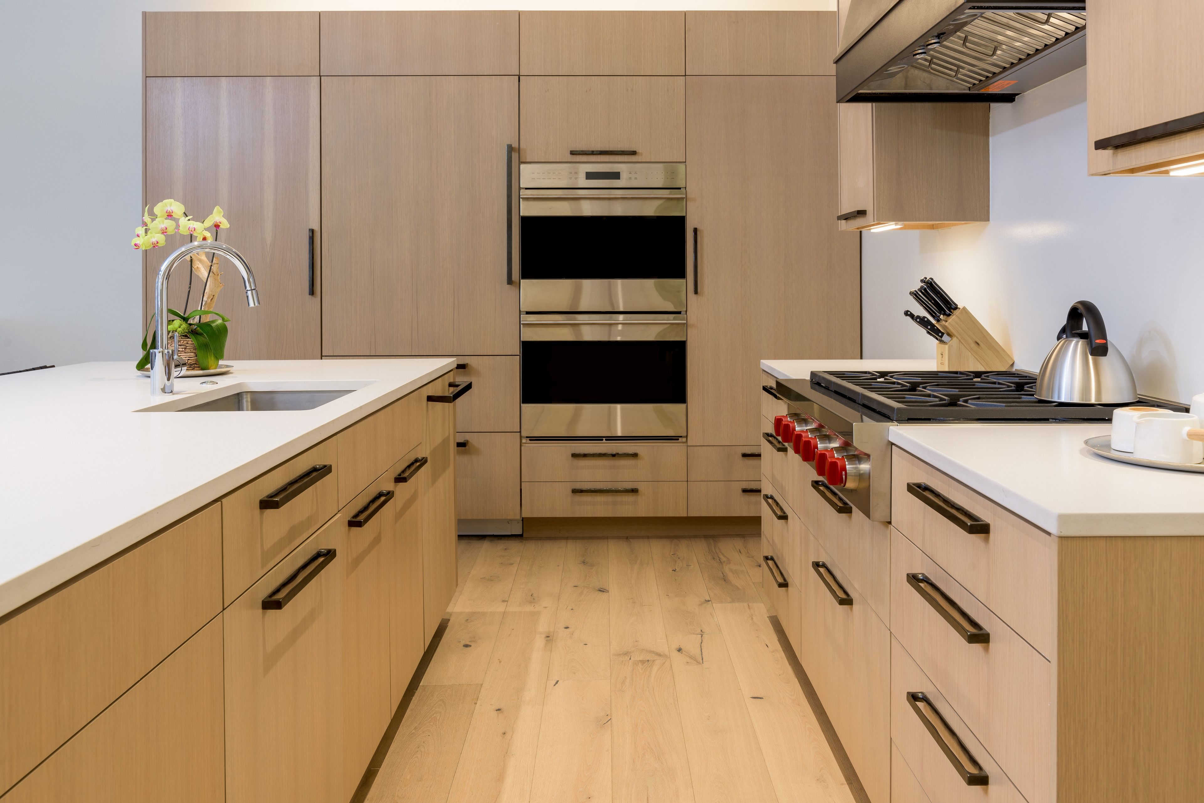 A modern kitchen with wooden cabinets, stainless steel appliances, and a white countertop.