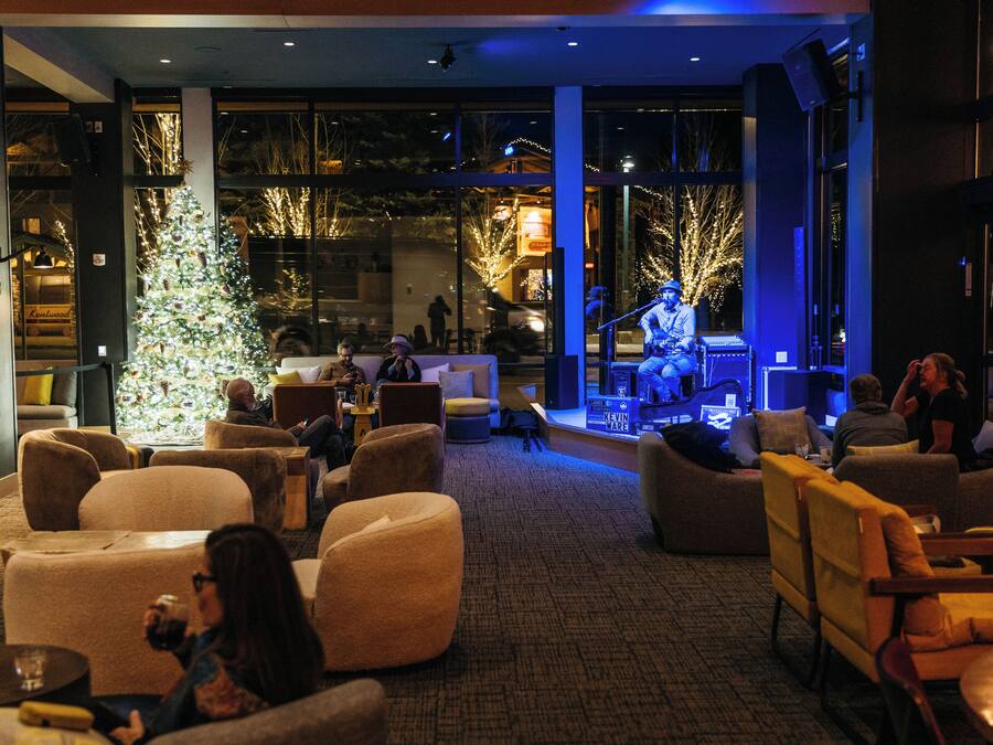A modern lounge area with comfortable seating, a Christmas tree, and a stage for performances.