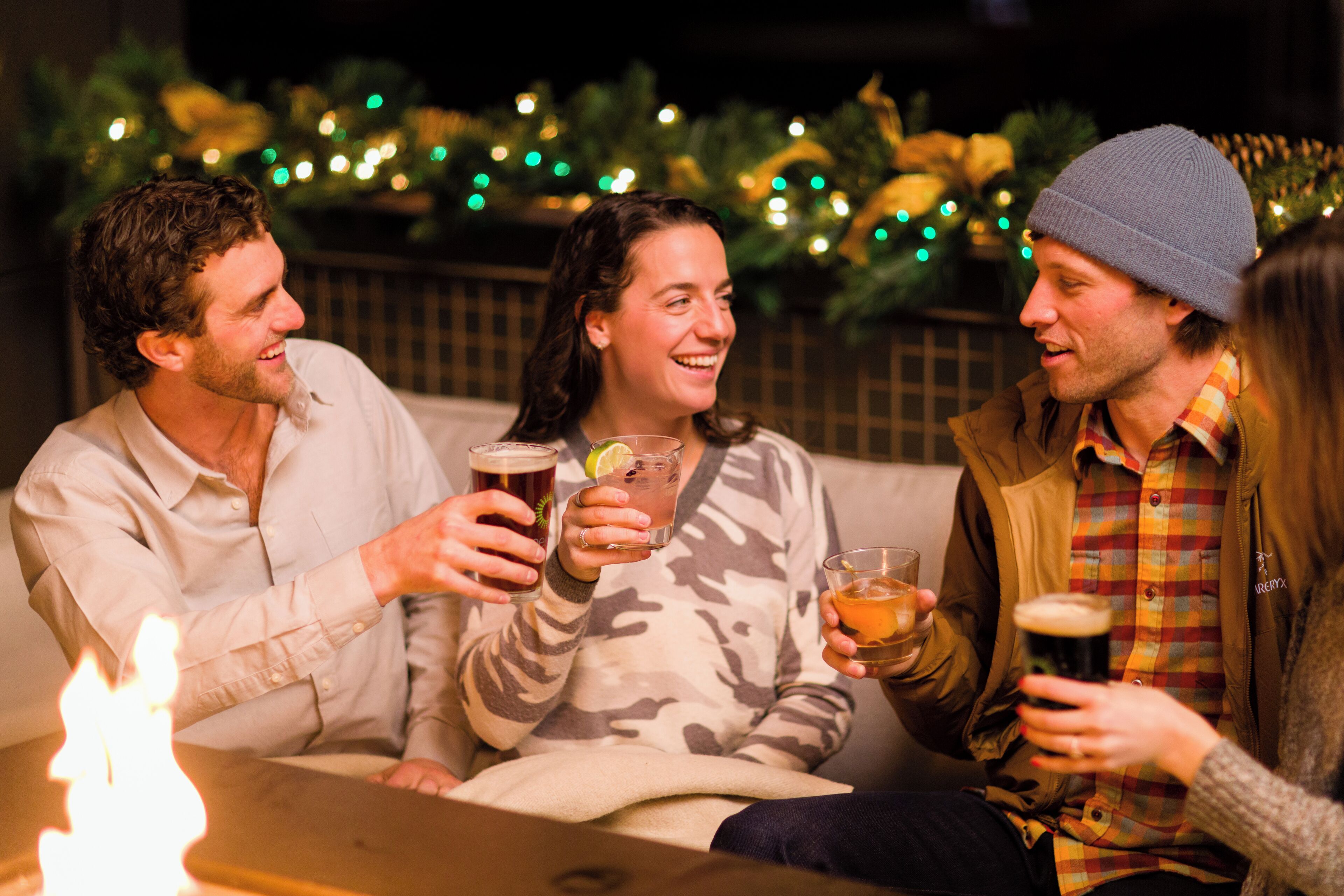 Three people sitting on a couch, holding drinks.