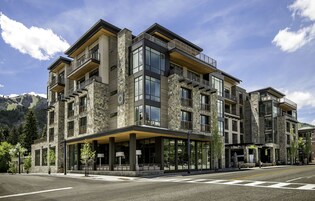 Un hotel de varios pisos con fachada de piedra, ventanas amplias y un área de entrada cubierta.