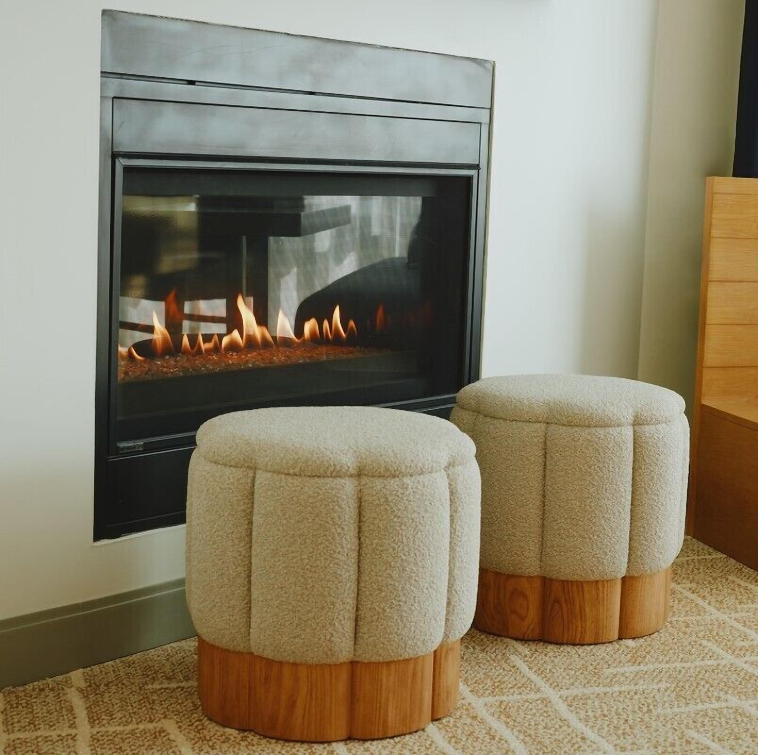 A modern fireplace with a glass front, flanked by two wooden ottomans.
