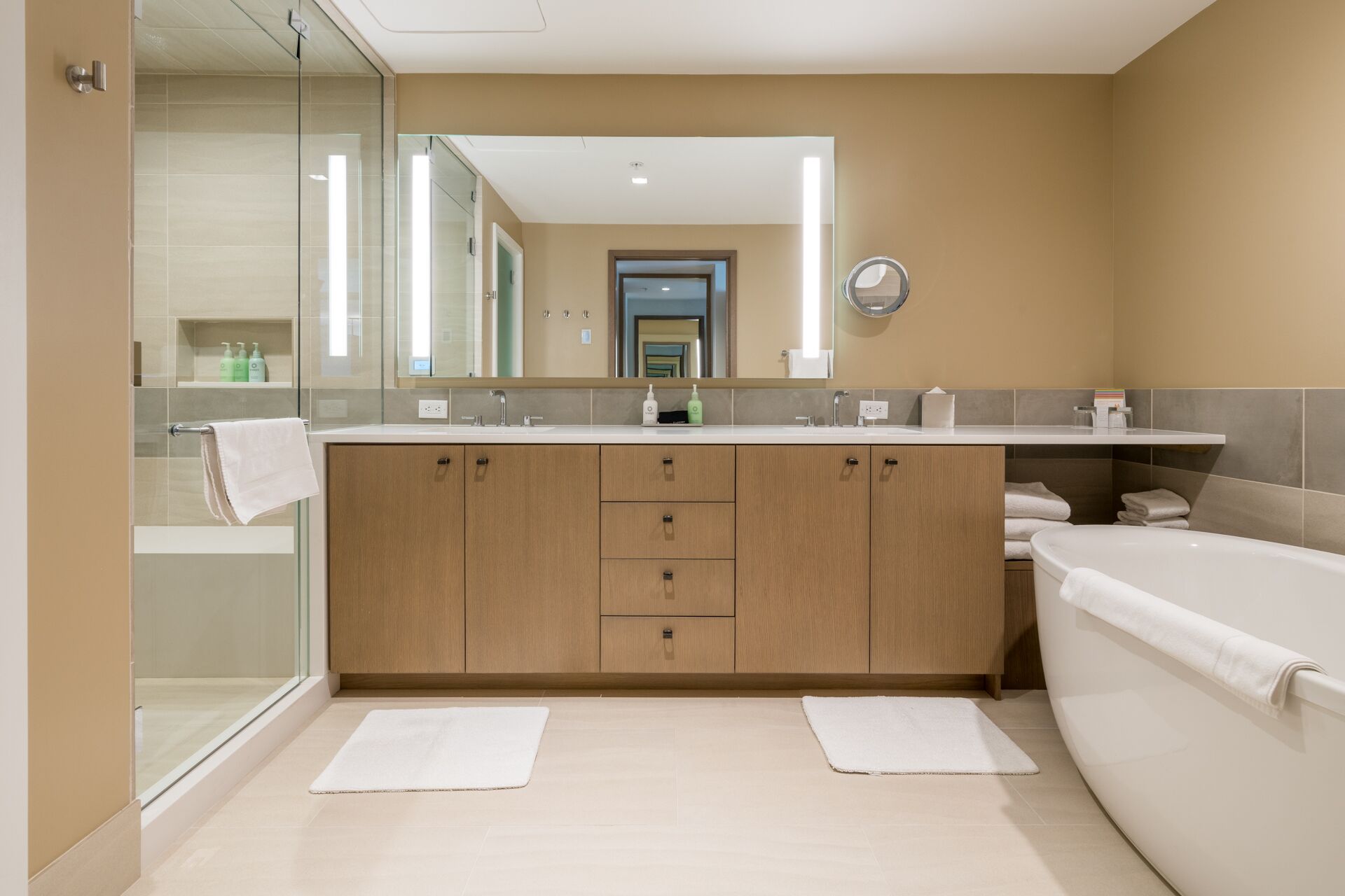 A modern bathroom with a glass shower enclosure, a large mirror, and a separate bathtub.