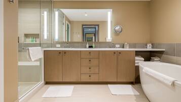 A modern bathroom with a glass shower enclosure, a large mirror, and a separate bathtub.