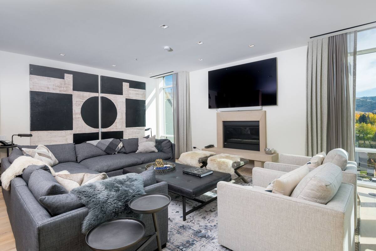 Un salon moderne avec un canapé d’angle, une table basse et une cheminée.