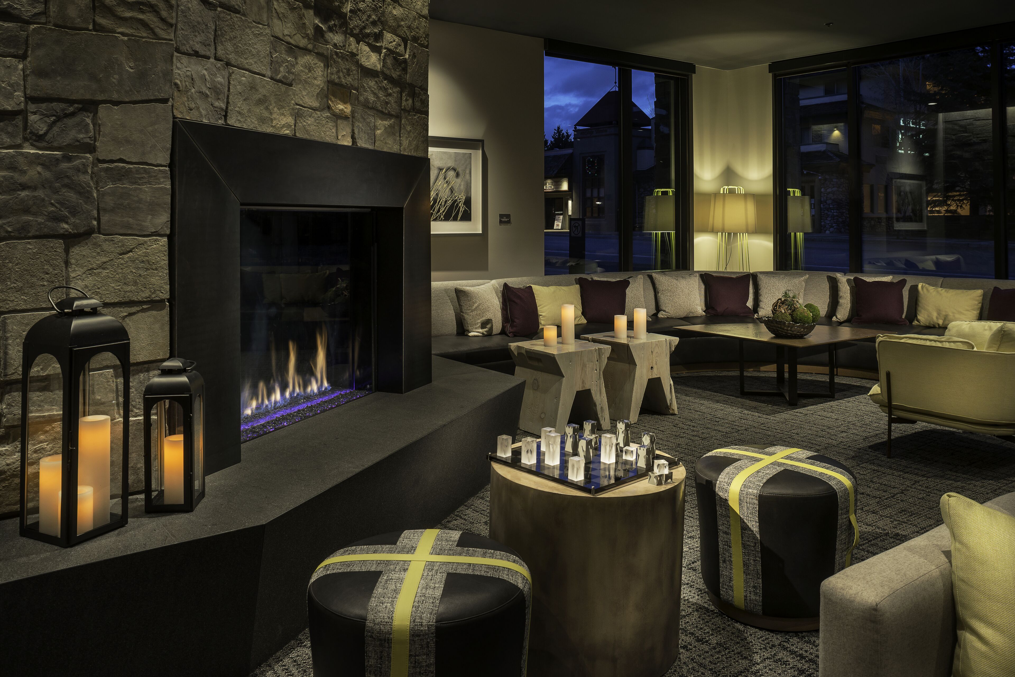 A modern lounge area with a stone fireplace, comfortable seating, and a view of the outside.
