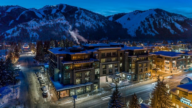 A modern hotel with multiple floors, large windows, and a view of snow-covered mountains. - Limelight Hotel Ketchum (Ketchum)