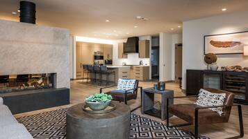 A modern living room with a fireplace, a dining area, and a kitchen in the background.