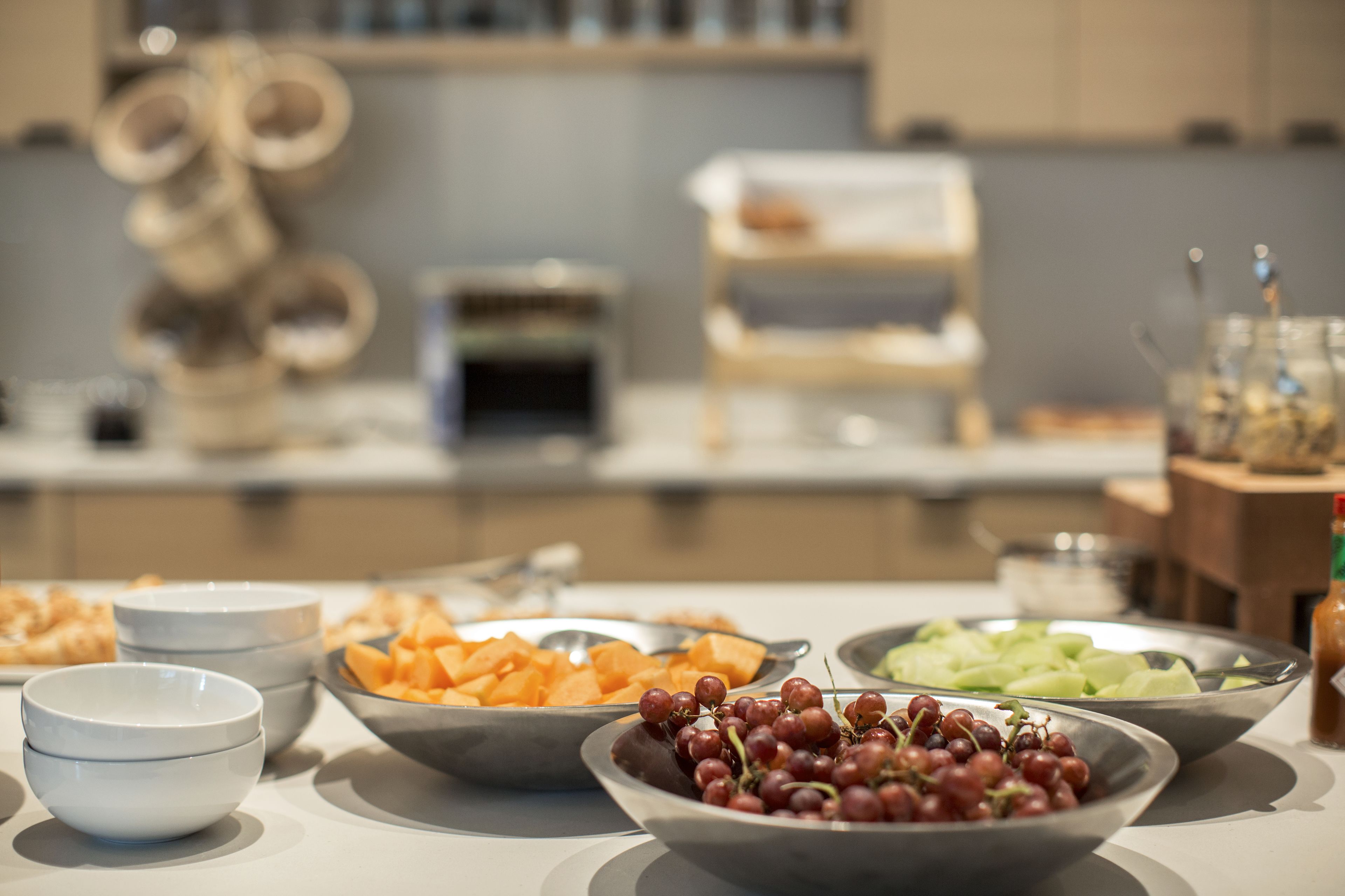 A buffet table with various food items including grapes, melon, and other fruits.