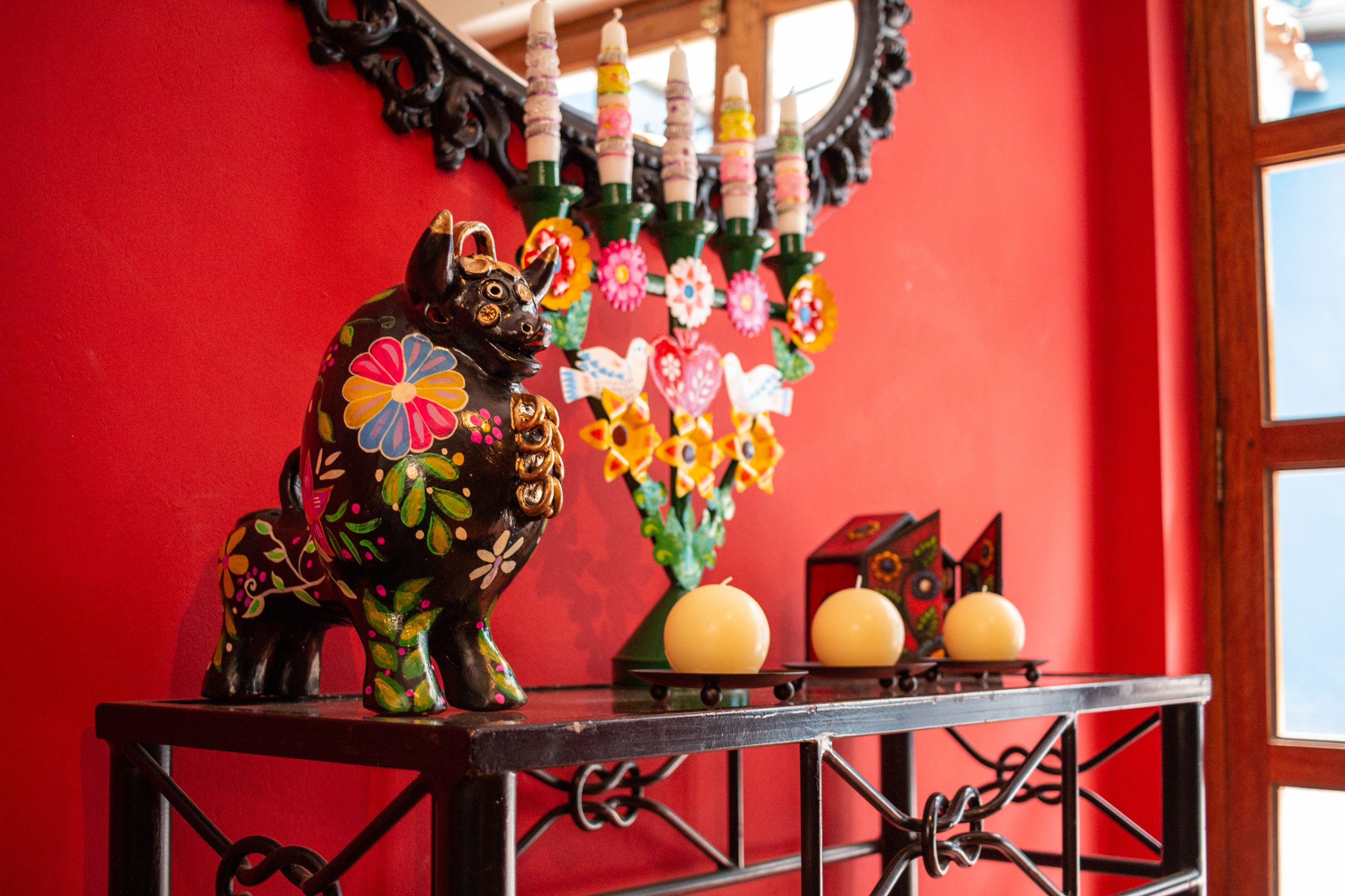 A decorative ceramic elephant on a table with candles and flowers in the background.