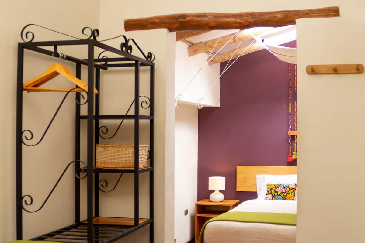 A room with a bunk bed, a hanging chair, and a shelf unit.