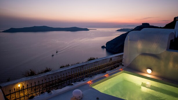 Ein Sonnenuntergangsblick vom Hotelbalkon über ein ruhiges Meer, mit Pool und weißem Zaun.