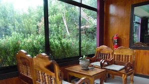 A room with wooden furniture, a table, and a view of greenery outside. - PhuTubkaek View House (Krabi)