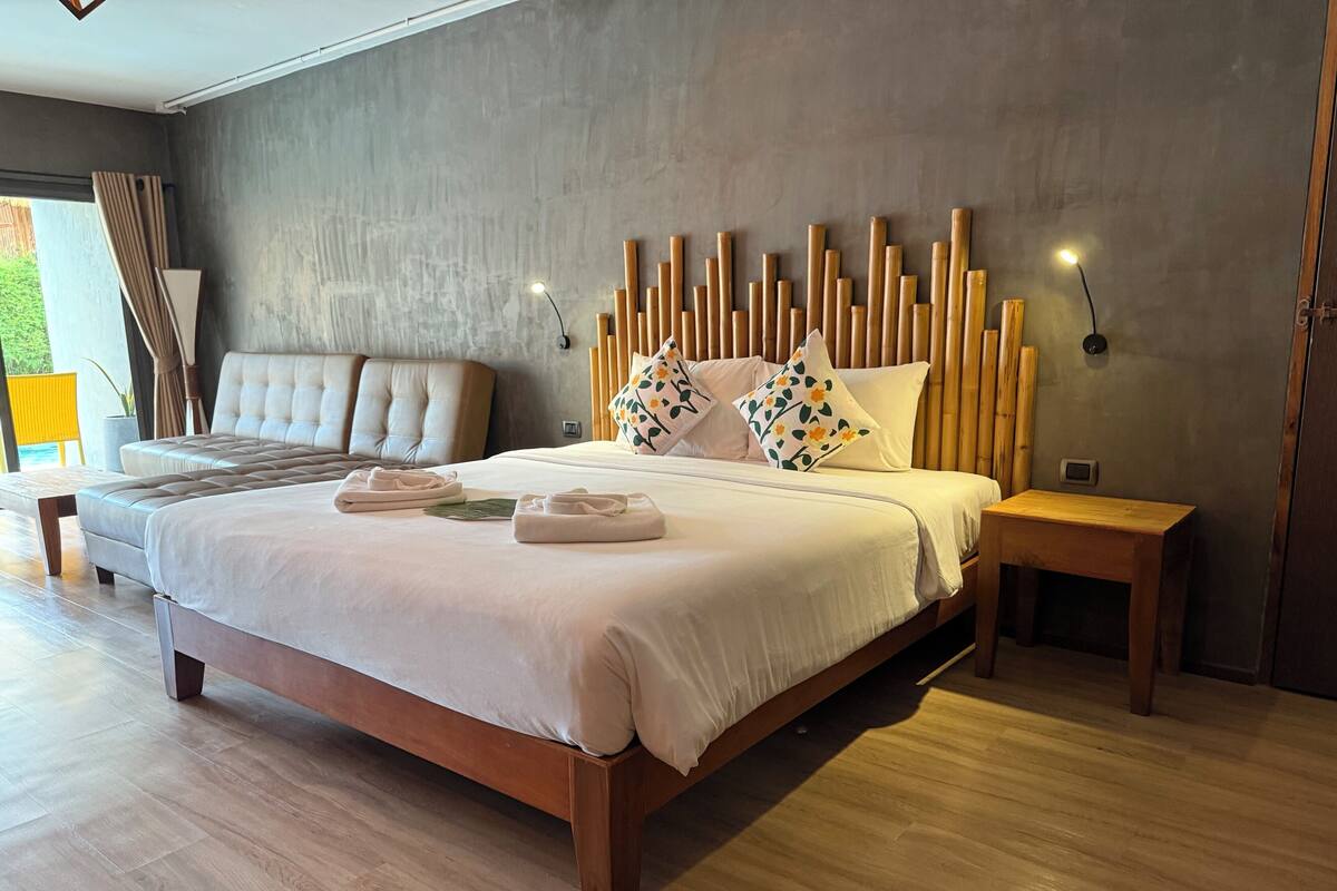 A modern bedroom with a large bed, wooden headboard, and bedside tables.