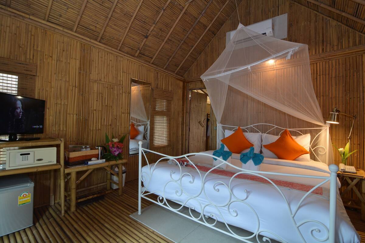 A room with a bed, a television, a desk, and a small refrigerator.