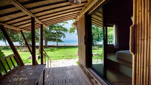 A covered outdoor seating area with a view of the sea and a grassy landscape. - Anyavee Krabi beach resort (Krabi)