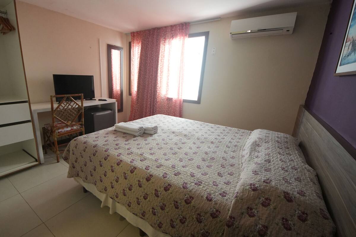 Une chambre à coucher comprenant un lit, un bureau, une chaise, une armoire et un appareil de climatisation.