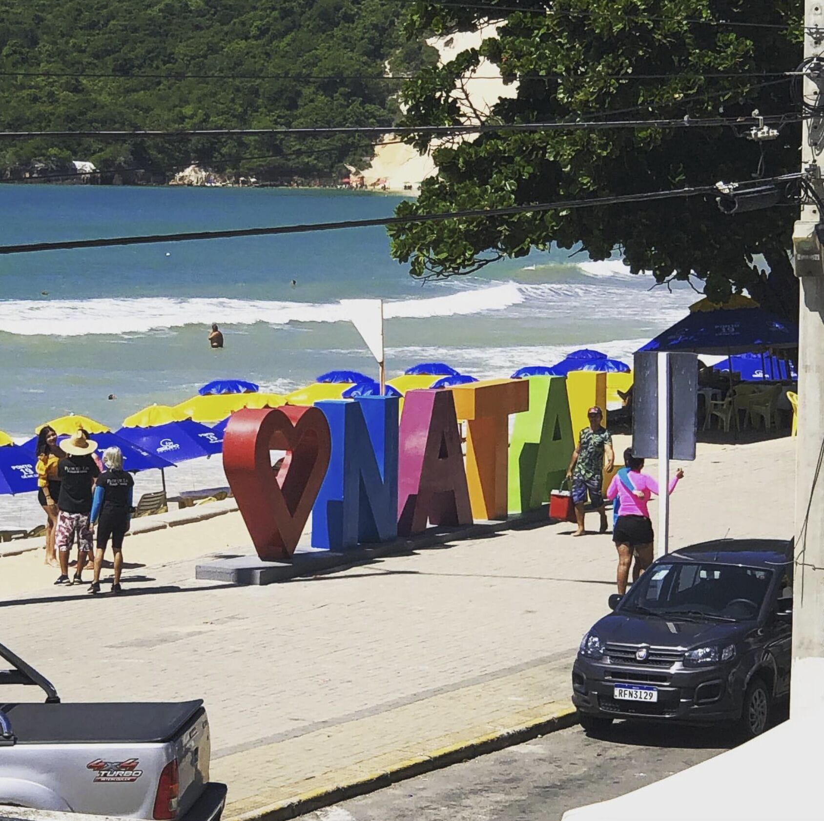 A beachside view with a large colorful sign spelling 'NATURA'.