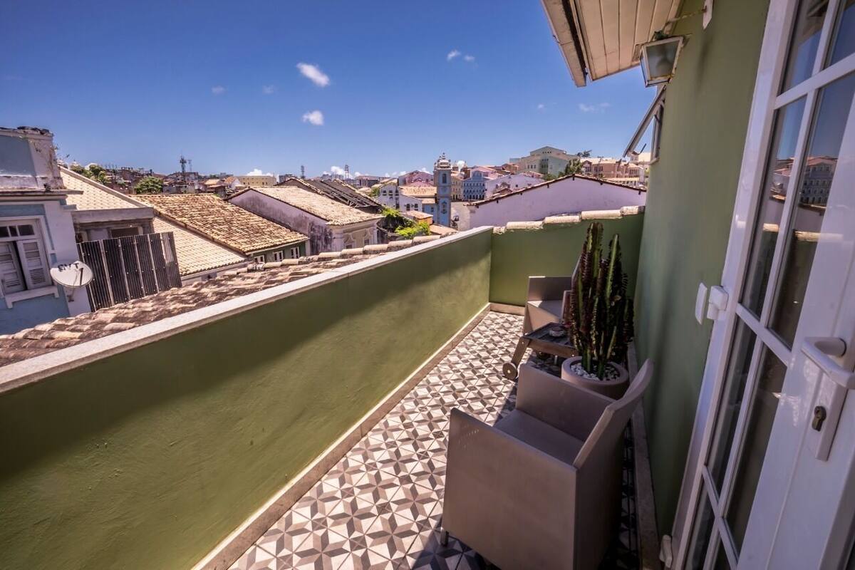 A balcony with a geometric tile floor, a potted plant, and a view of the cityscape.