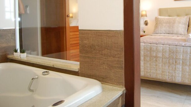 Un baño con bañera, espejo y puerta de madera.