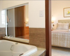 A bathroom with a bathtub, a mirror, and a wooden door.