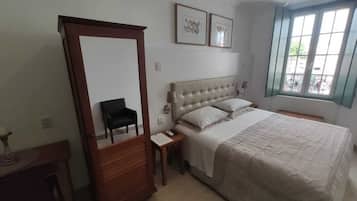 Un dormitorio con una cama grande, un armario, una mesita de noche y una ventana con vistas.