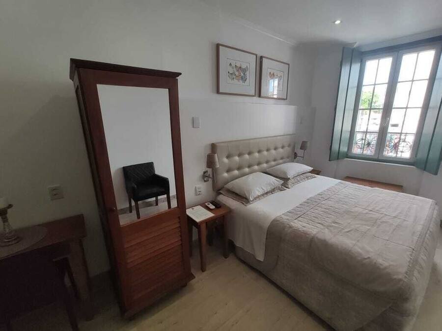 Un dormitorio con una cama grande, un armario, una mesita de noche y una ventana con vistas.