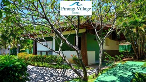 Un exuberante jardín con un edificio que dice "Pirangi Village Hotel".