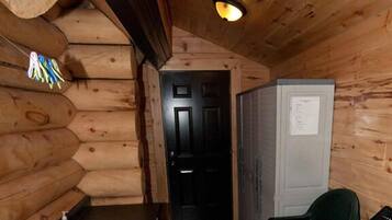 A compact log cabin interior with a kitchen area, including a sink, a refrigerator, and a door leading to another room.