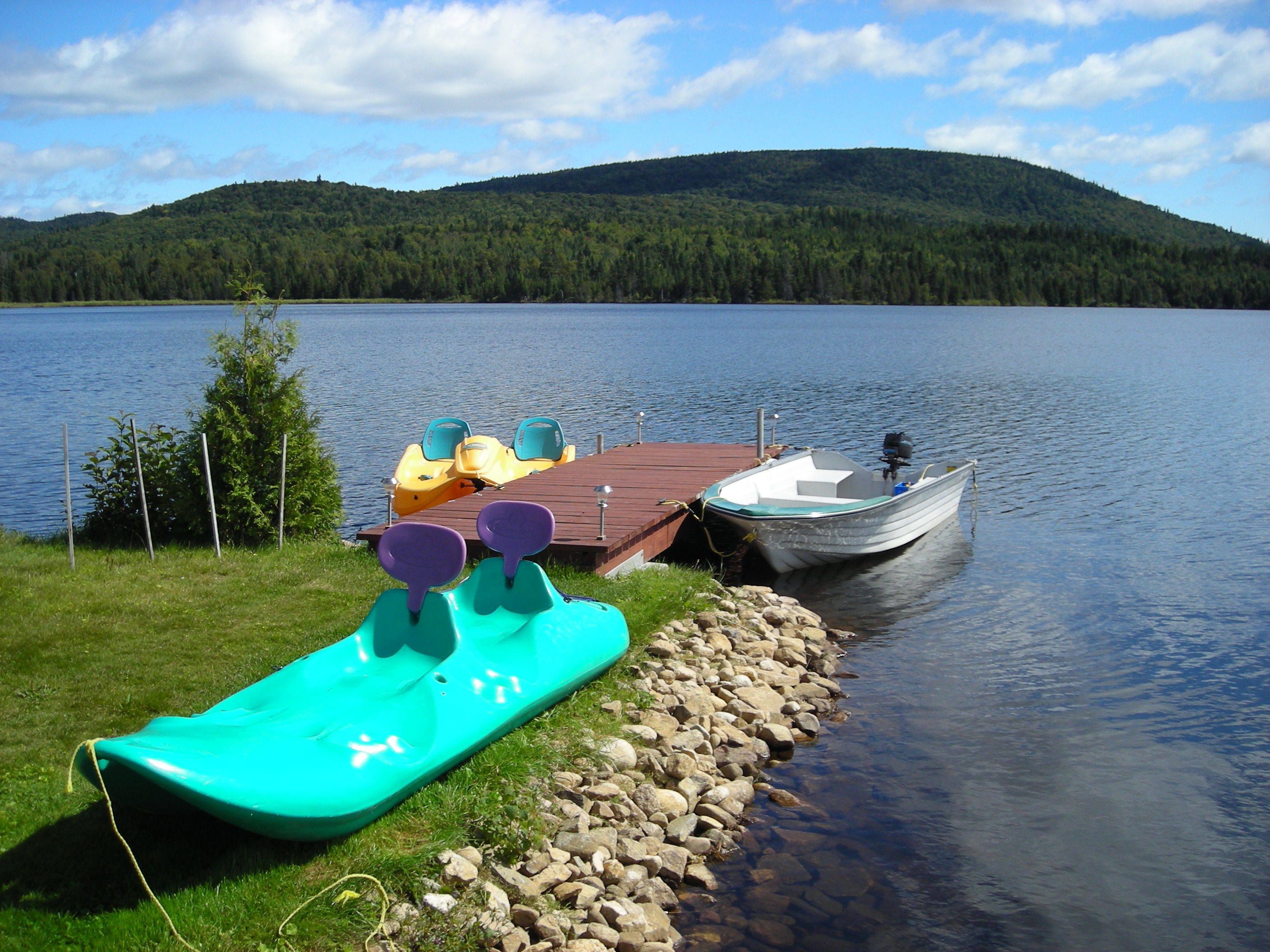 A lakeside dock with kayaks and a small boat.