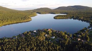 Um lago rodeado por colinas arborizadas, com um pequeno povoado ao primeiro plano.