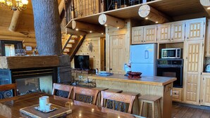 Un interior rústico de madera con comedor, cocina y chimenea.