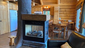 Interior acogedor de una cabaña con chimenea, muebles de madera y una zona de comedor.