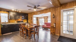 A wooden interior with a dining area, kitchen, and a cozy living space.
